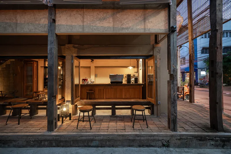 Open storefront with timber counter, exposed structural columns and overhead beams at dusk