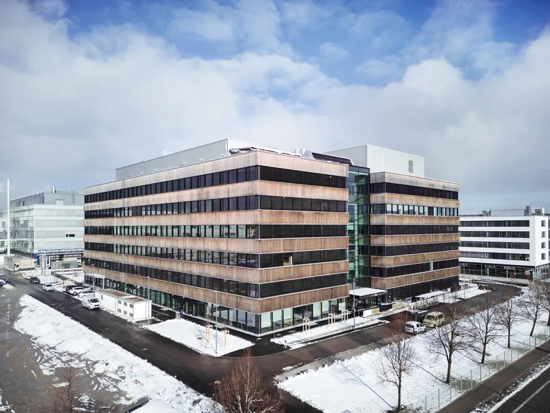 Aerial view of the horizontally banded facade with alternating copper and dark panels in winter