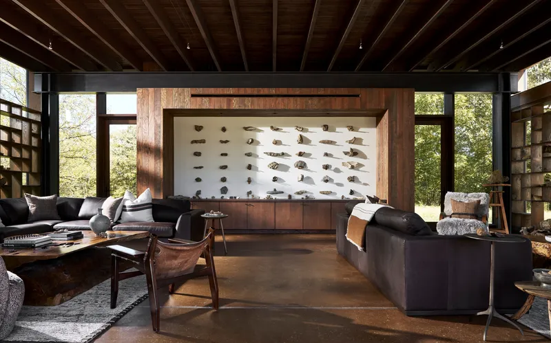 Living room with exposed timber ceiling beams and a backlit rock specimen display framed in walnut