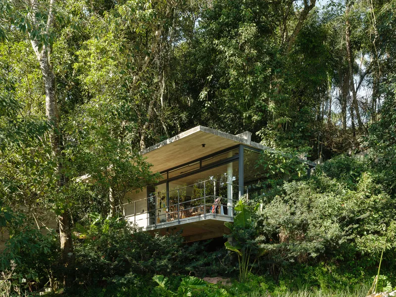 Elevated glass-walled pavilion with timber ceiling and deck nestled among eucalyptus trees and tropical plantings