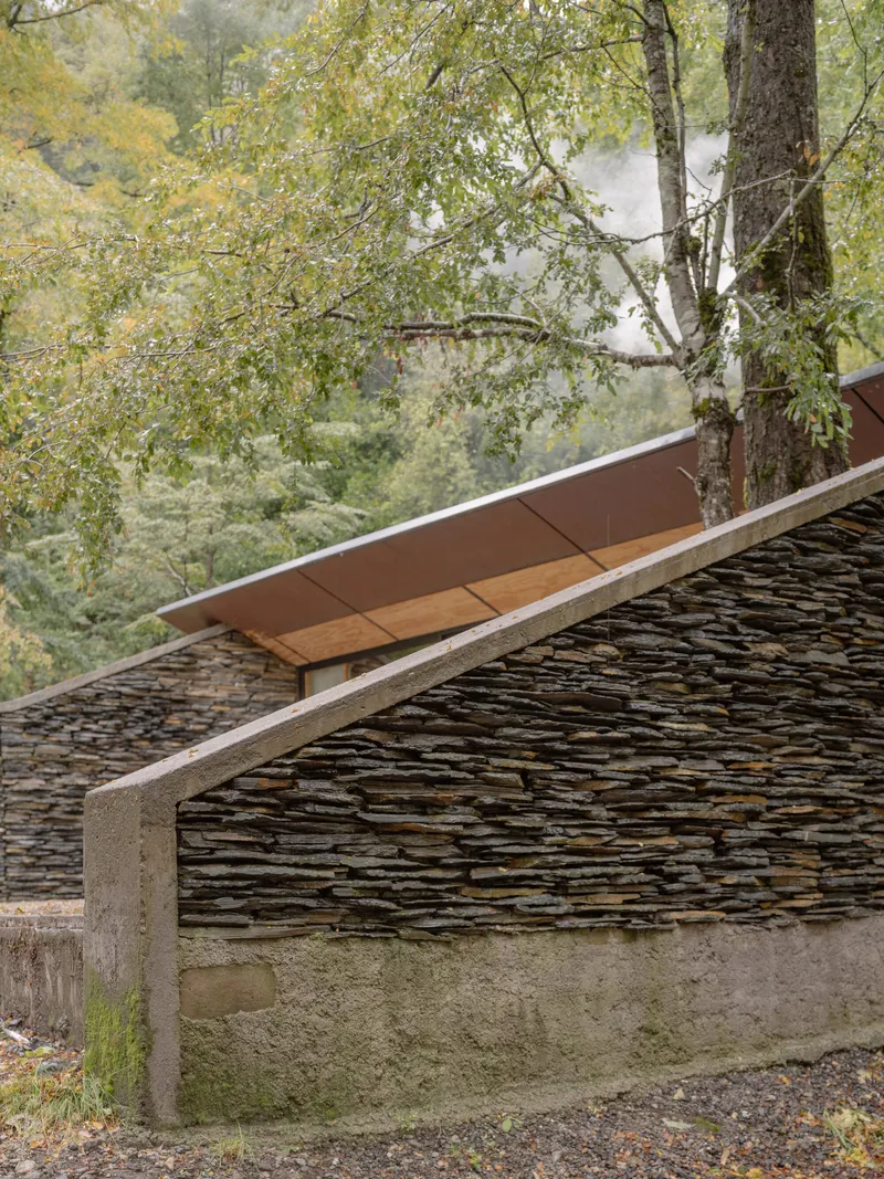Detail of cantilevered roof with timber soffit and concrete edge above dry-stacked slate wall