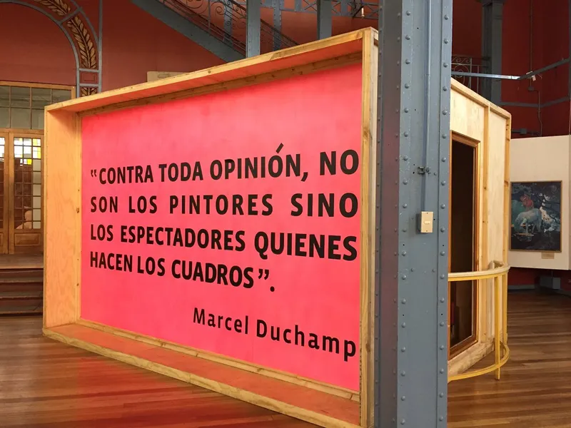 Freestanding timber-framed exhibition panel with coral-colored graphics beside a painted steel column