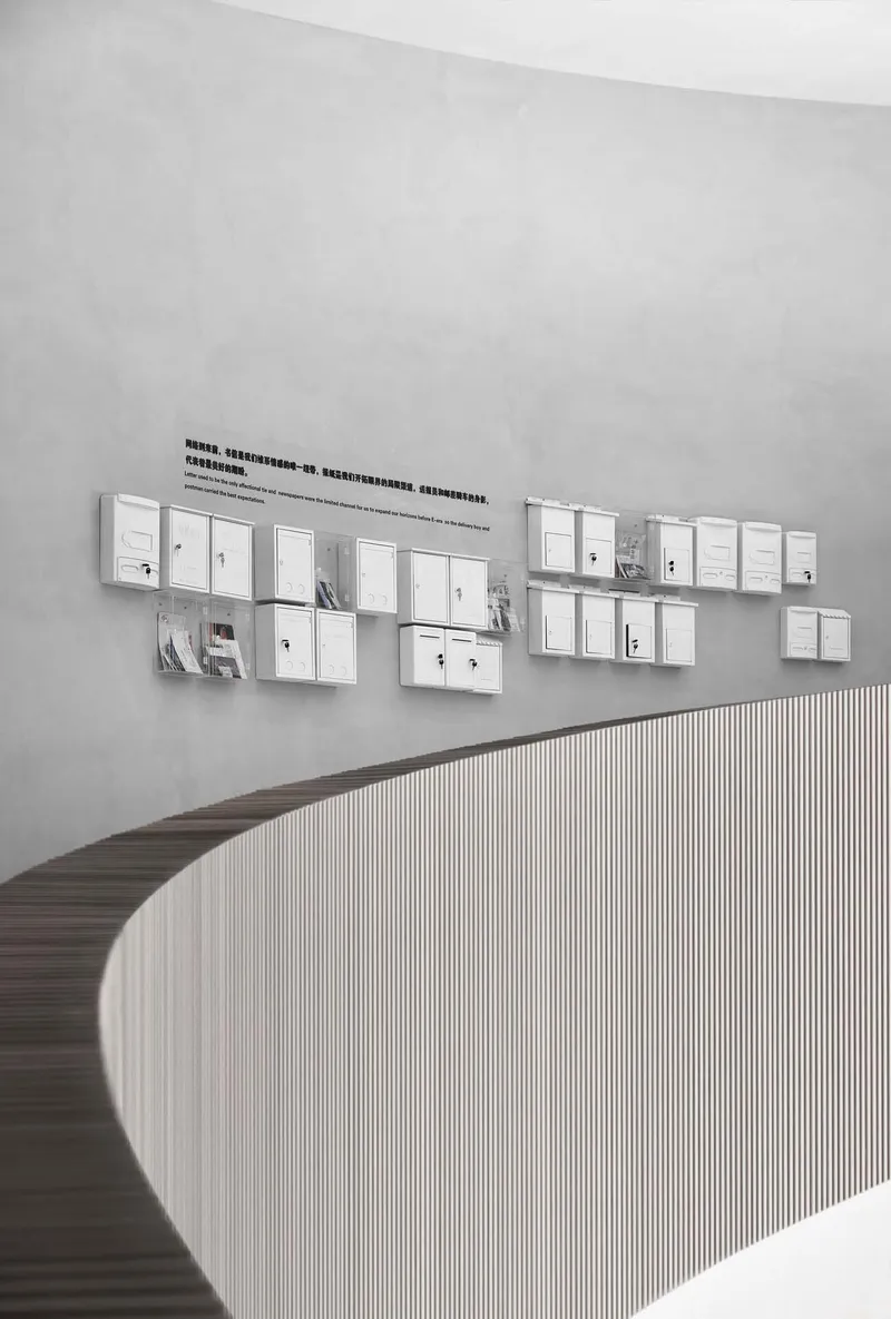 Curved reception desk with vertical wood slat cladding beneath a grid of white-framed display panels