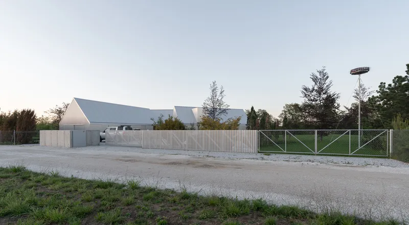 Street view of vertical timber fence and pitched metal roofs at dusk