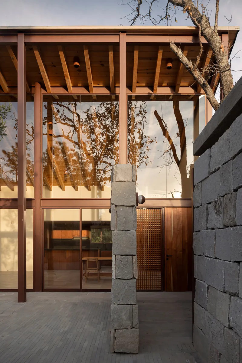 Covered terrace with exposed timber joists and a stacked stone column at twilight