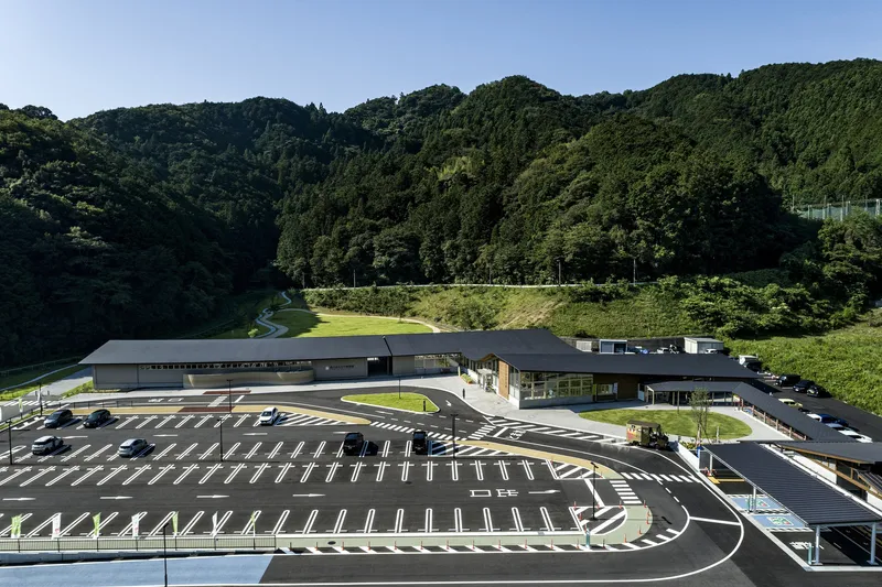 Aerial view of the curved complex with parking lot and forested mountain valley beyond