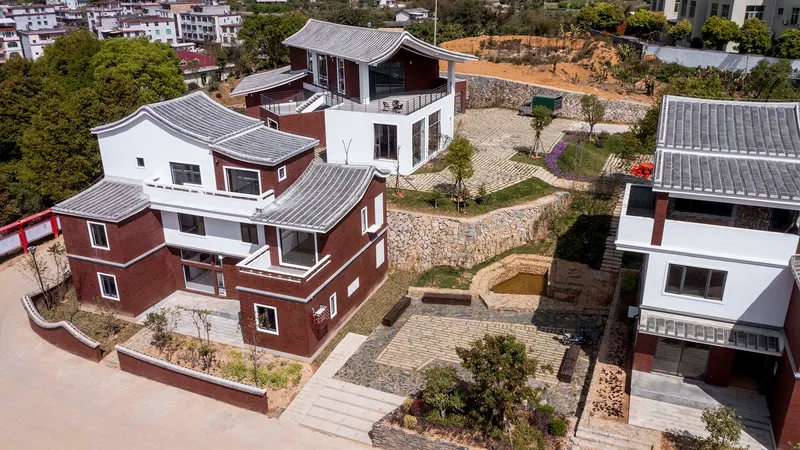 Aerial view of clustered housing volumes with red brick cladding and curved metal roofs among terraced courtyards
