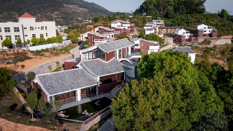 Aerial view of buildings with grey tile roofs surrounding a central courtyard pond and lawn