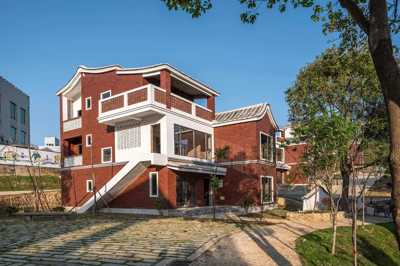Three-story brick house with white balconies and perforated screens facing a stone courtyard