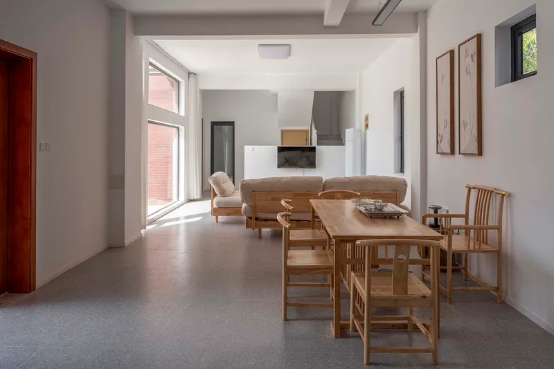 Open living and dining area with timber furniture and white walls under natural daylight
