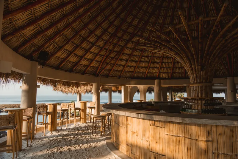 Interior view of circular bar with bamboo cladding under a radiating thatch ceiling structure