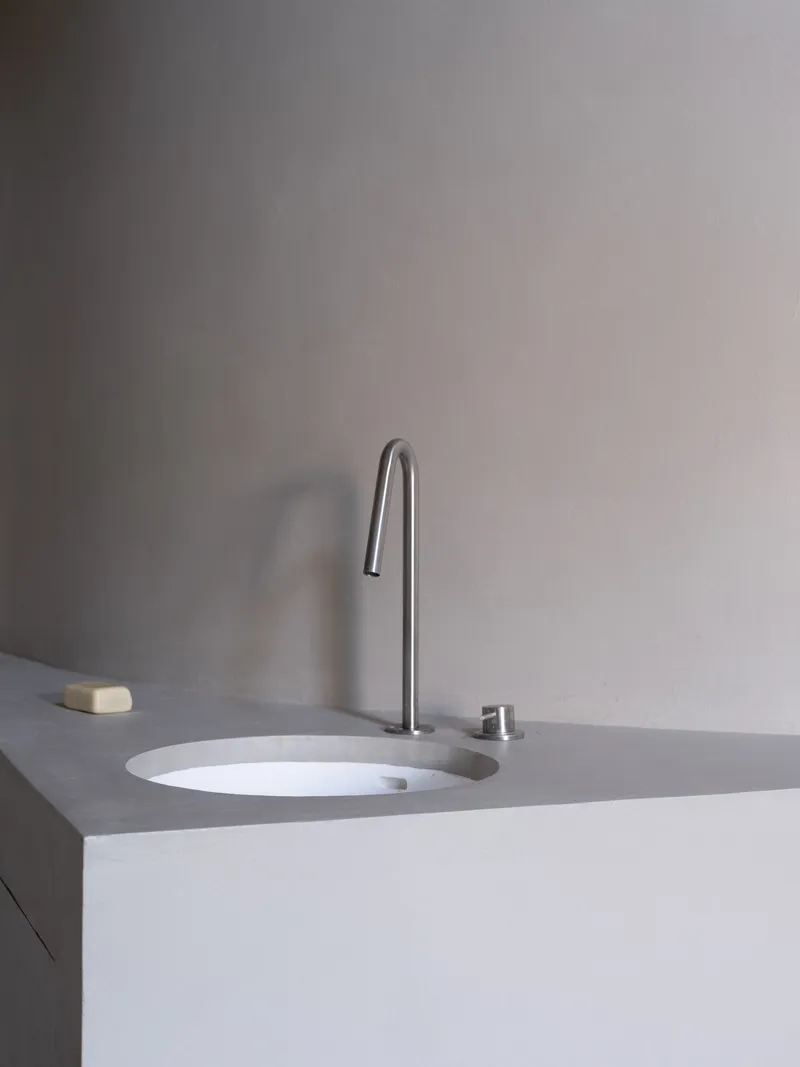 Close-up of integrated sink with high-arc tap and push button drain in pale grey countertop