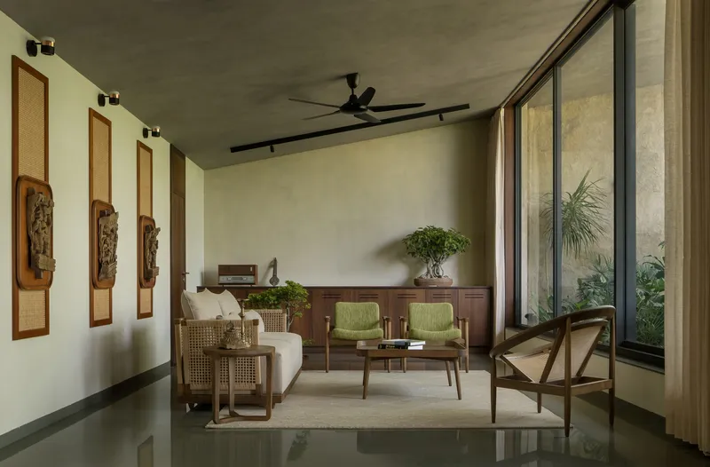 Living room with concrete ceiling, polished floor and full-height glazing overlooking internal garden