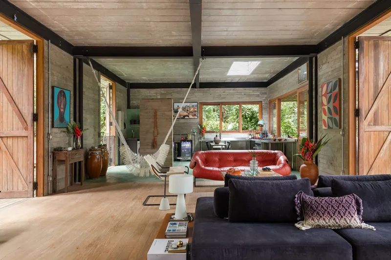 Open-plan interior with exposed black steel frame and timber ceiling beams under central skylight