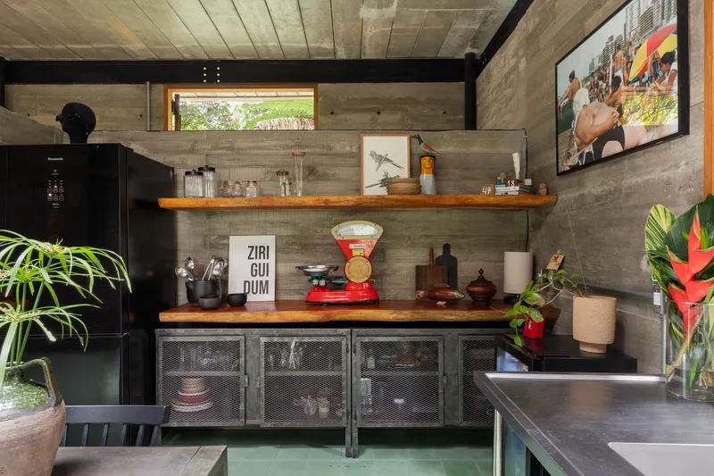 Kitchen area with open timber shelving and perforated metal cabinets below concrete walls