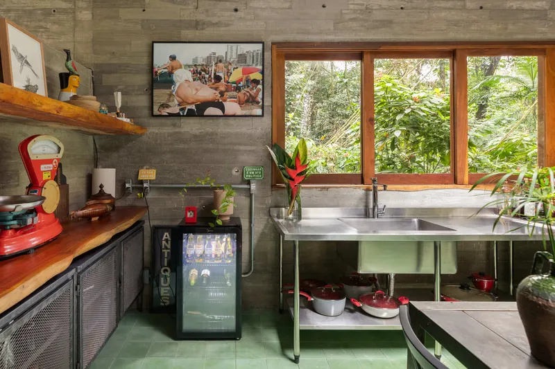 Kitchen counter with stainless steel sink facing timber-framed windows overlooking dense forest