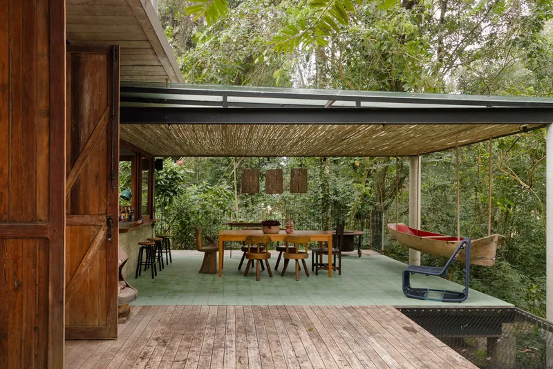 Covered terrace with woven ceiling panels and glass balustrade overlooking forest canopy