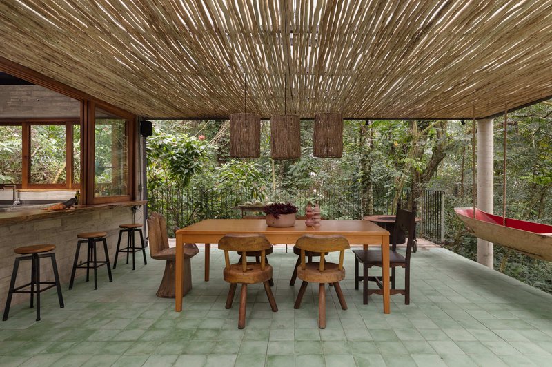 Dining area beneath woven bamboo ceiling with three pendant lights and views to forest