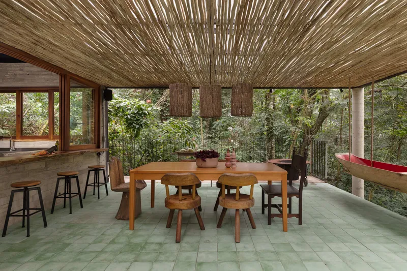 Dining area beneath woven bamboo ceiling with three pendant lights and views to forest