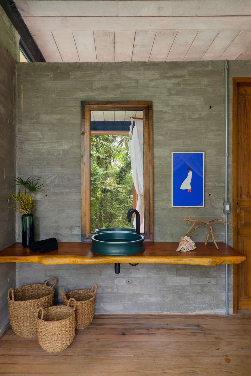Live-edge timber vanity with green basin against board-formed concrete walls and timber ceiling
