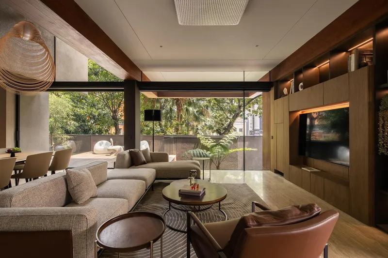 Living room with timber ceiling beams and floor-to-ceiling glazing opening to landscaped courtyard beyond