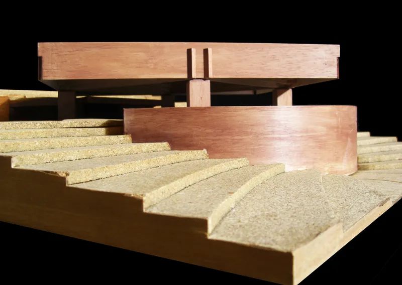 Close-up of the physical model showing timber columns supporting the raised volumes above stepped terrain