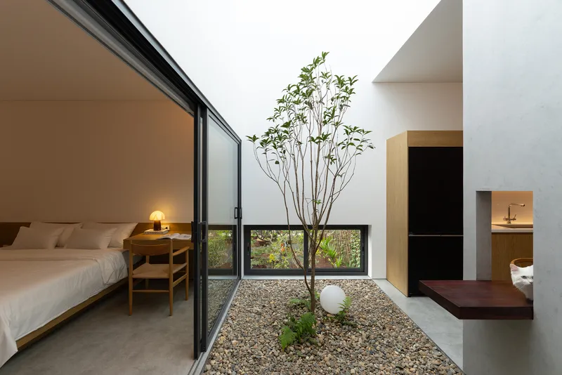 Interior courtyard with gravel bed and tree viewed from bedroom with glazed sliding doors