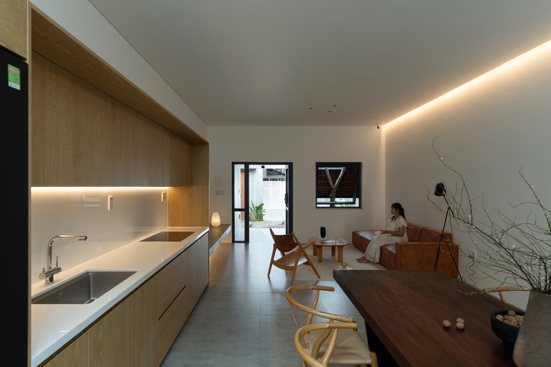Open kitchen and dining area with timber cabinetry and a person seated in the distance