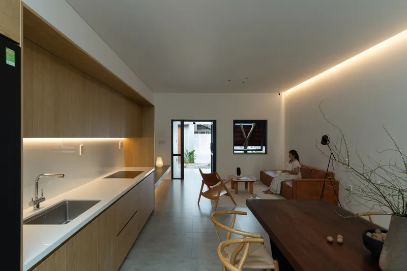 Open kitchen and dining area with timber cabinetry and a person seated in the distance