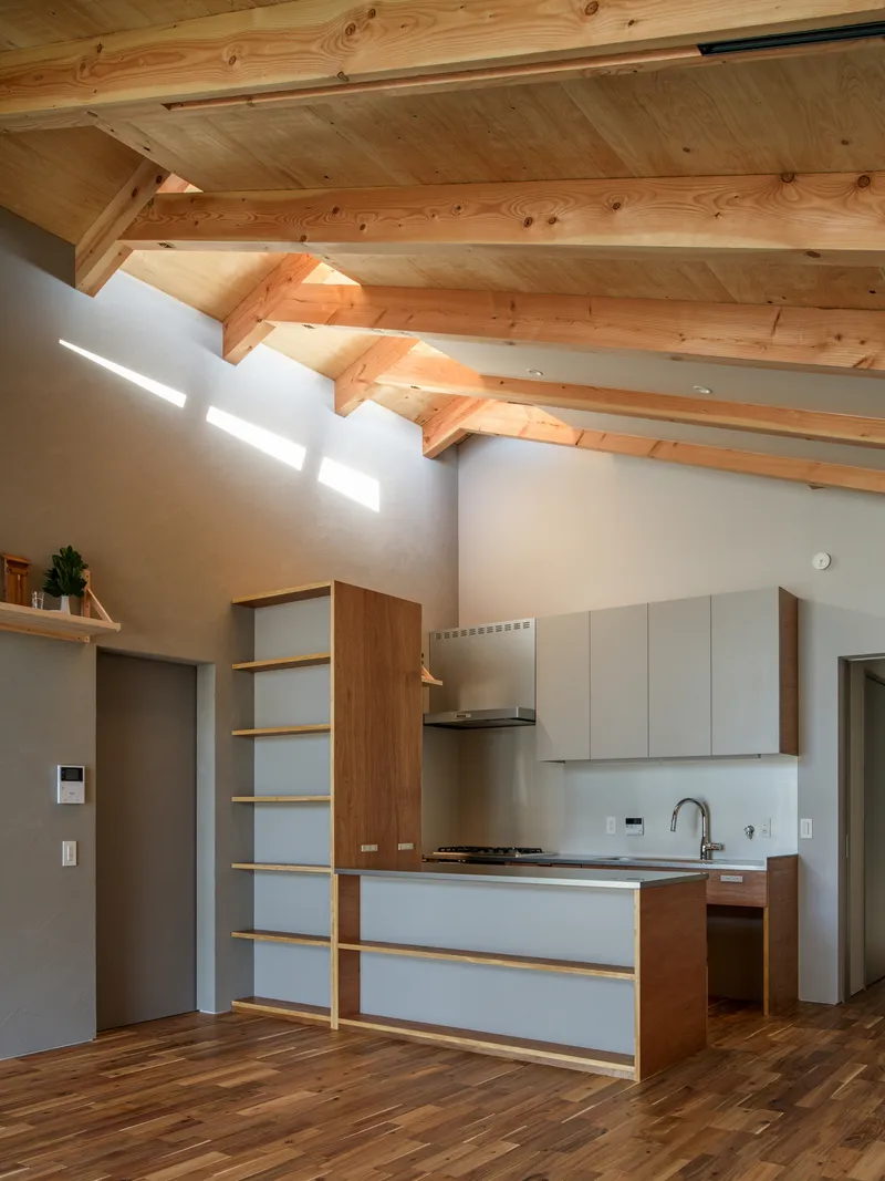 Kitchen galley with timber and white cabinetry below exposed rafters and a clerestory window slot