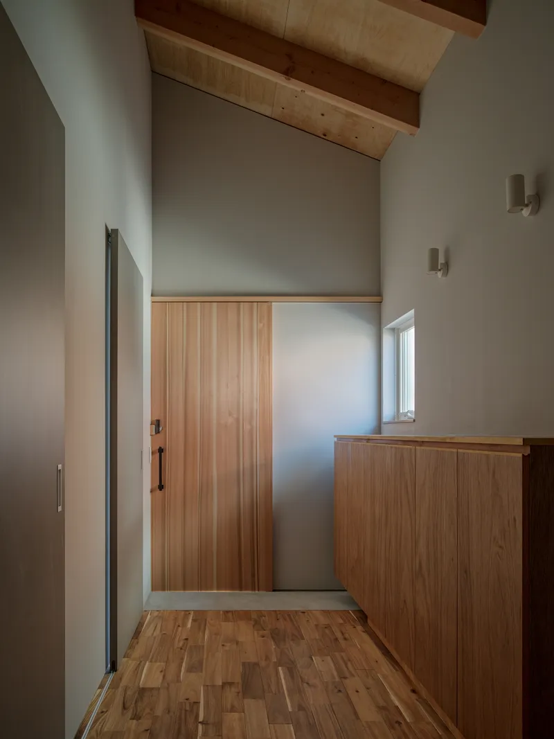 Entry hall with timber door and built-in cabinet under vaulted ceiling with exposed wood rafters