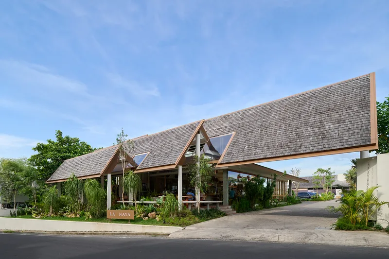 Street view of the shingled gable roofs with clerestory windows amid lush tropical plantings