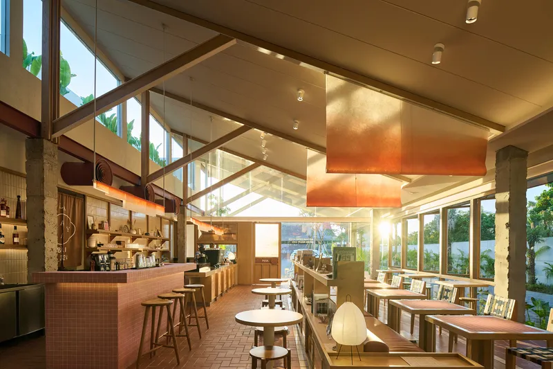 Interior cafe space with pink tile bar, timber ceiling beams and suspended orange pendant fixture