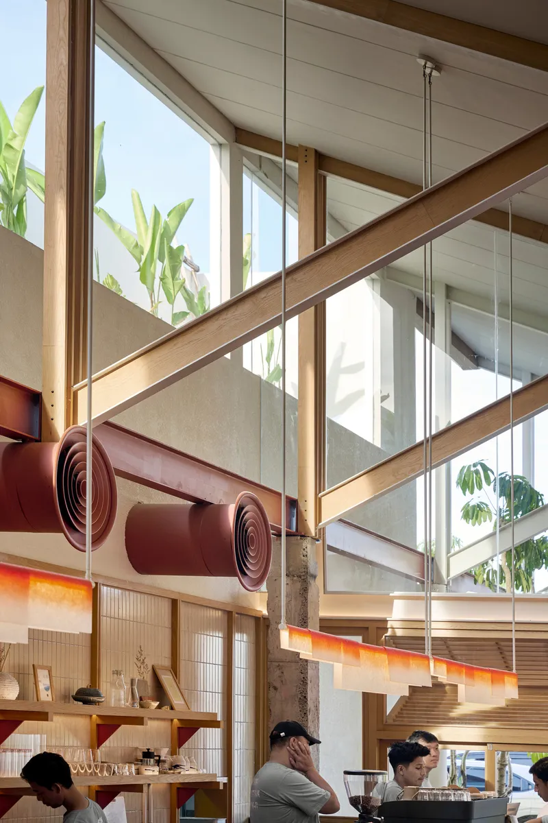Detail of scrolled maroon metal canopy element above timber counter with diners seated below