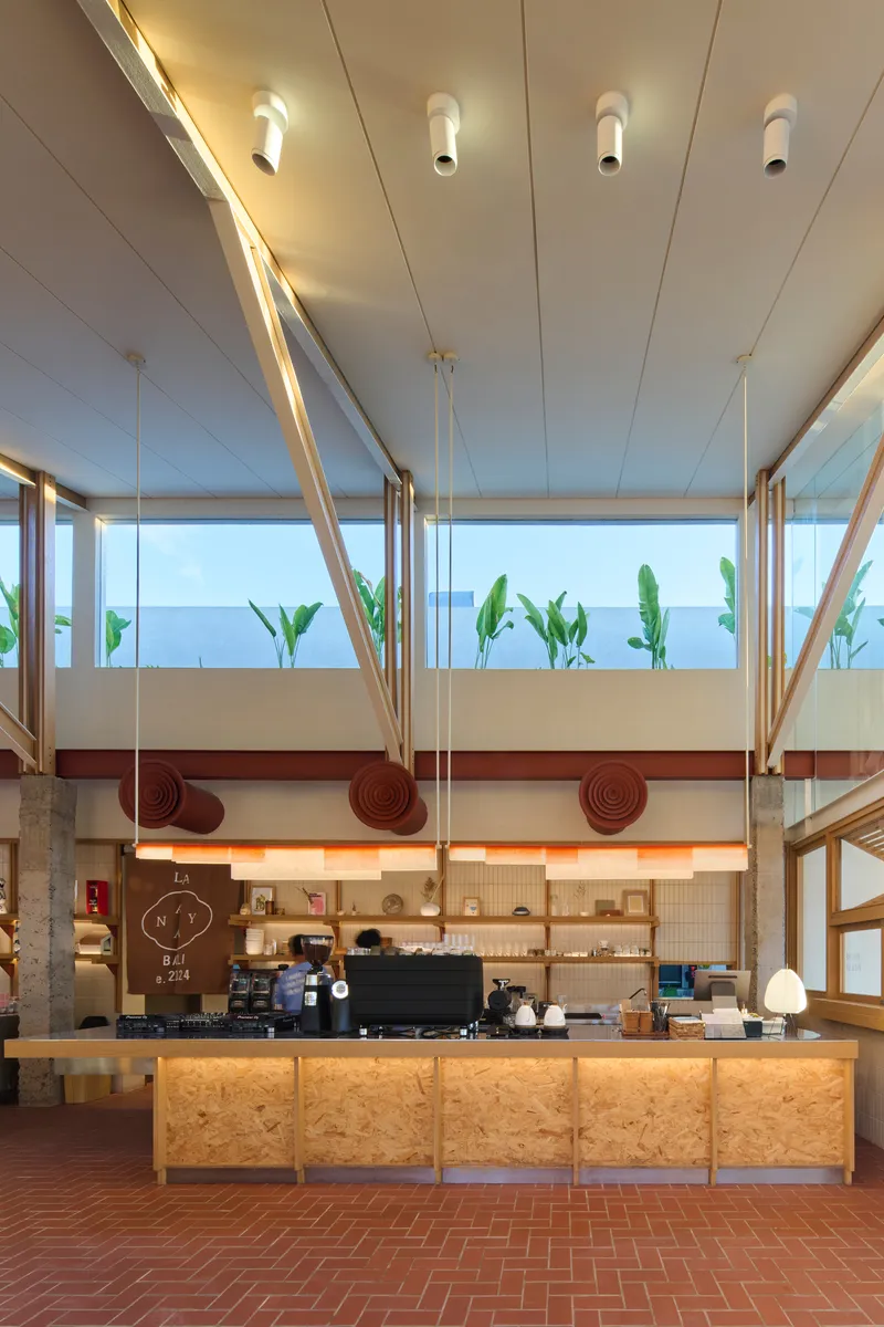 Coffee counter with plywood base, maroon decorative discs, and planted clerestory windows above