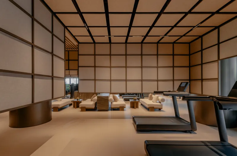 Fitness studio with gridded translucent wall panels framing low seating platforms and exercise equipment