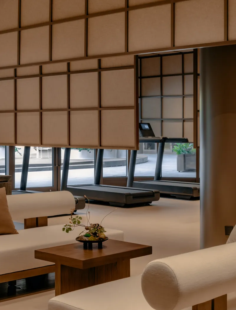 Corner seating nook with timber table and bonsai beneath suspended gridded translucent wall panels