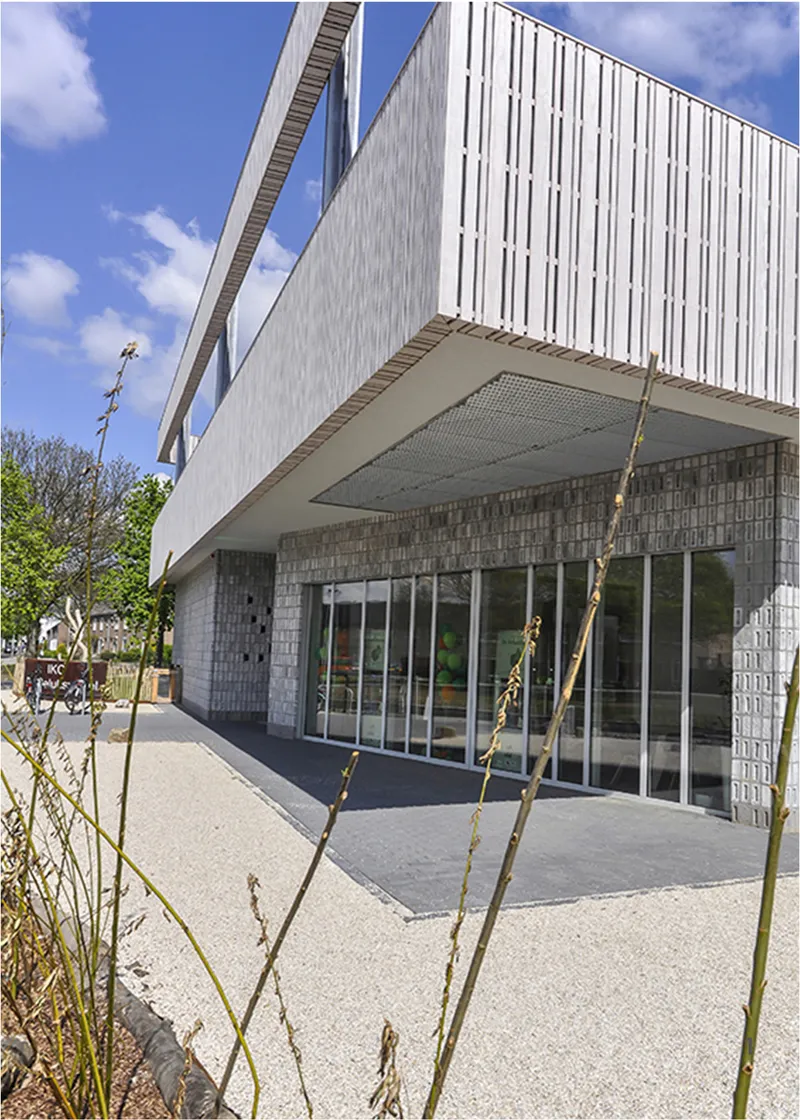Textured façade and deep overhang create a sheltered entrance for young learners.