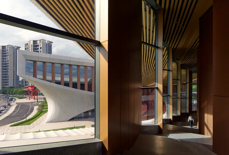 Interior hallway with striped timber ceiling and angled window framing a view of the curved facade