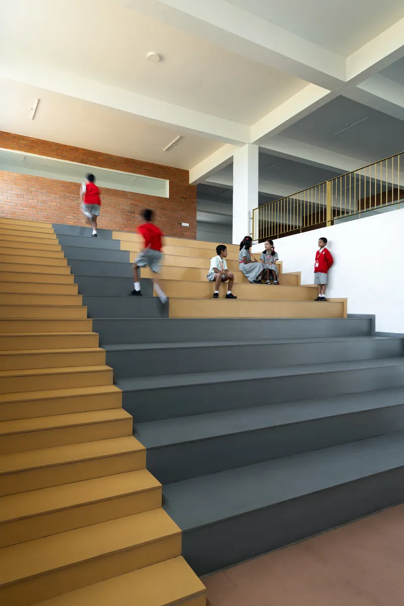 Interior staircase with alternating yellow and grey treads where students gather on the landings