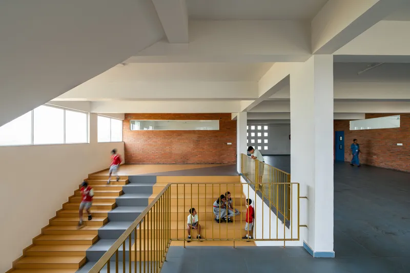 Multi-level atrium view showing the split stair and brass-colored railings under coffered concrete ceilings