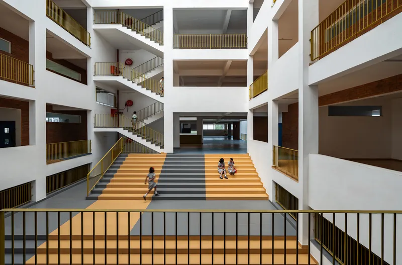 Central atrium with multi-story white balconies and striped stair where children play on the steps