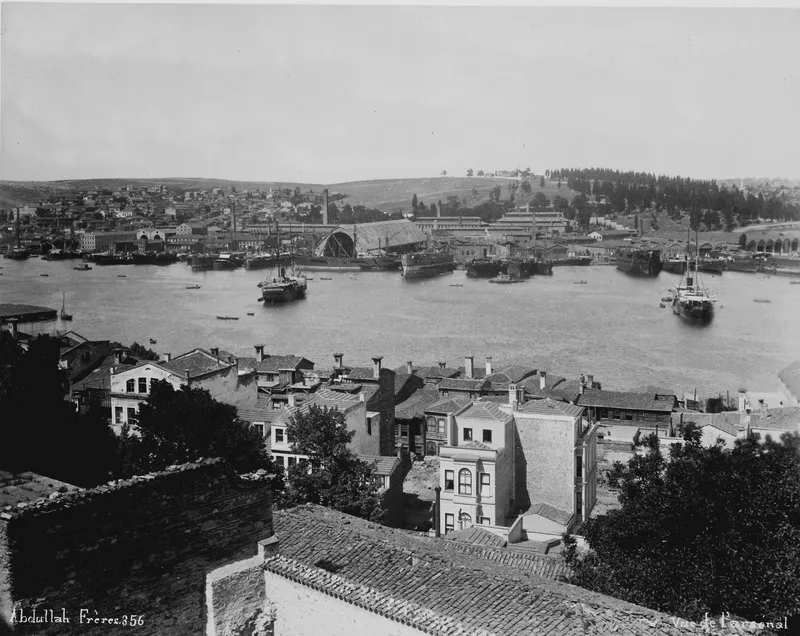 Historic photograph of a harbor with ships and residential buildings climbing the hillside beyond