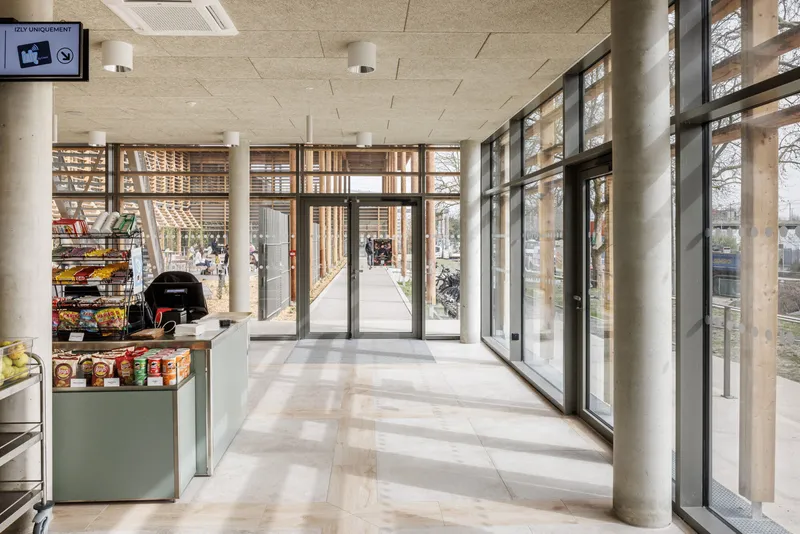 Entrance lobby with cylindrical concrete columns and floor-to-ceiling glazing framed by timber brise-soleil
