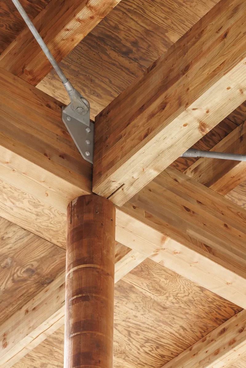 Detail of timber post and beam junction with steel bracket and exposed wood grain