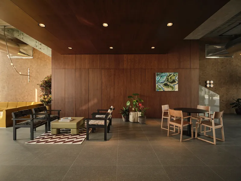 Seating area with walnut wall panels and concrete ceiling coffers illuminated by recessed downlights