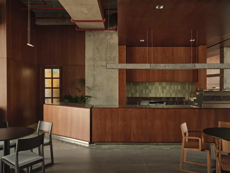 Kitchen counter with green mosaic backsplash, wooden cabinetry, and suspended woven light fixture overhead