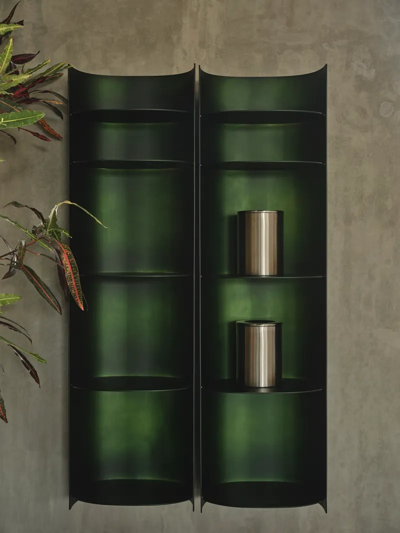 Top-down view of curved dark green metal shelving units with two stainless steel vessels and potted plants