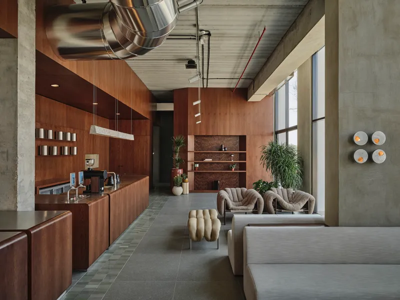 Reception area with walnut paneling and exposed concrete columns flanking gray tile floor