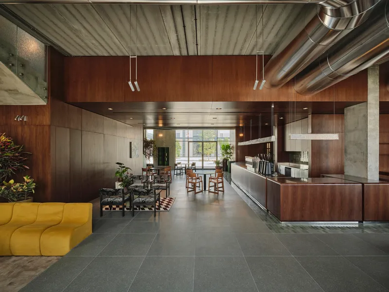 Long view through lobby showing suspended wood ceiling panels and reception desk beneath exposed ductwork